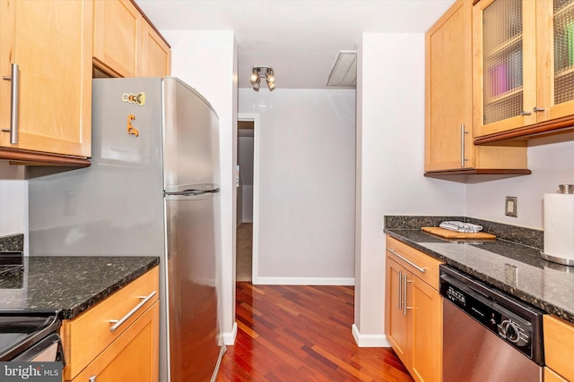 kitchen featuring appliances with stainless steel finishes, dark stone counters, and dark hardwood / wood-style flooring