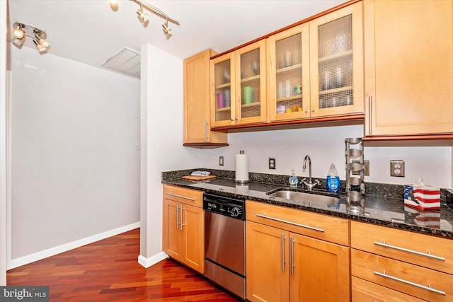 kitchen featuring stainless steel dishwasher, sink, dark wood-type flooring, and dark stone counters