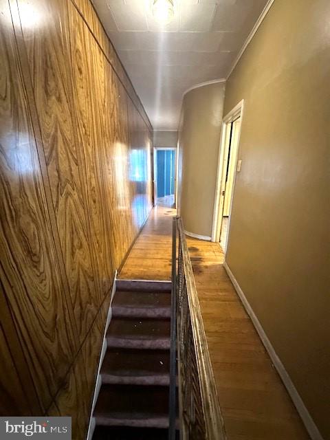 stairway featuring wood walls, hardwood / wood-style floors, and crown molding