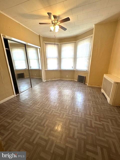 empty room featuring dark parquet flooring and ceiling fan