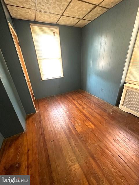 unfurnished bedroom featuring wood-type flooring and a paneled ceiling