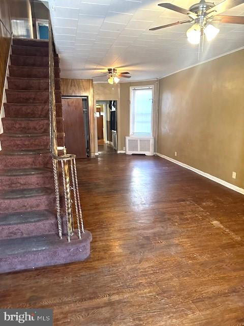 unfurnished living room featuring ceiling fan, dark hardwood / wood-style floors, and radiator