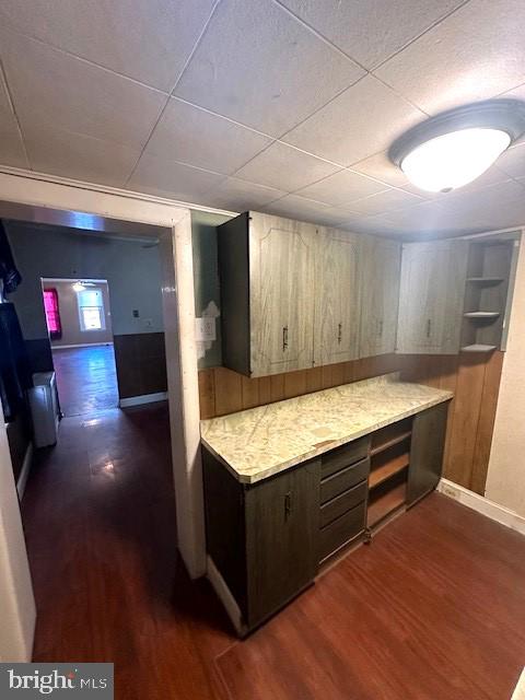 kitchen with wood walls, dark brown cabinetry, and dark hardwood / wood-style flooring