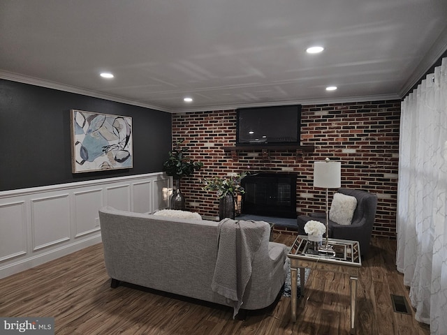 living room featuring crown molding, dark hardwood / wood-style floors, and a brick fireplace