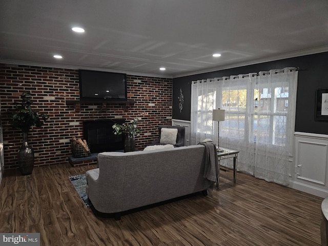 living room featuring crown molding, brick wall, a fireplace, and dark hardwood / wood-style flooring