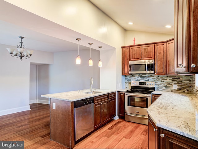 kitchen with pendant lighting, appliances with stainless steel finishes, sink, and kitchen peninsula