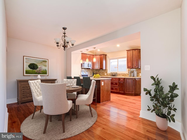 dining area with light hardwood / wood-style floors and a chandelier