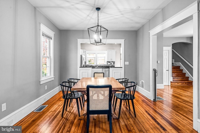 dining space with sink, an inviting chandelier, and hardwood / wood-style floors