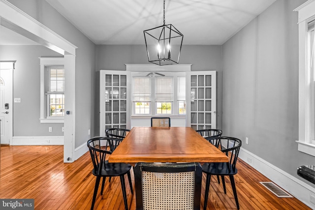 dining area with hardwood / wood-style flooring and an inviting chandelier