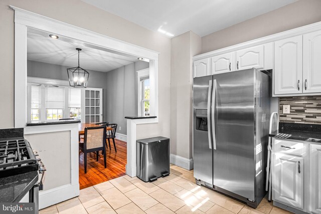 kitchen featuring light hardwood / wood-style flooring, stainless steel fridge, pendant lighting, an inviting chandelier, and white cabinets