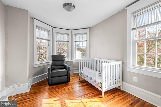 bedroom featuring hardwood / wood-style floors, a nursery area, and multiple windows