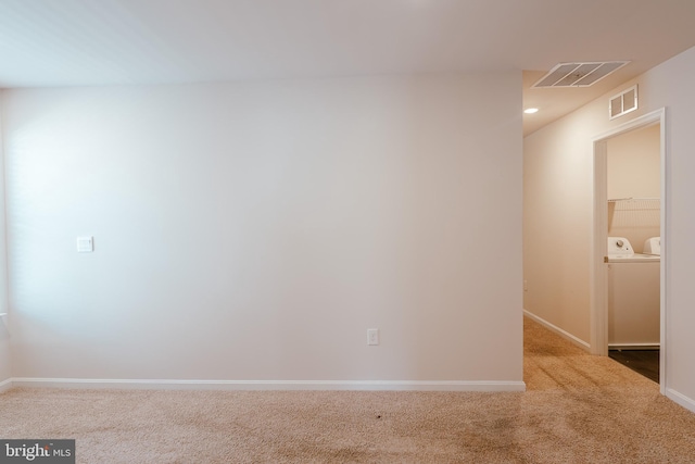 carpeted spare room featuring independent washer and dryer