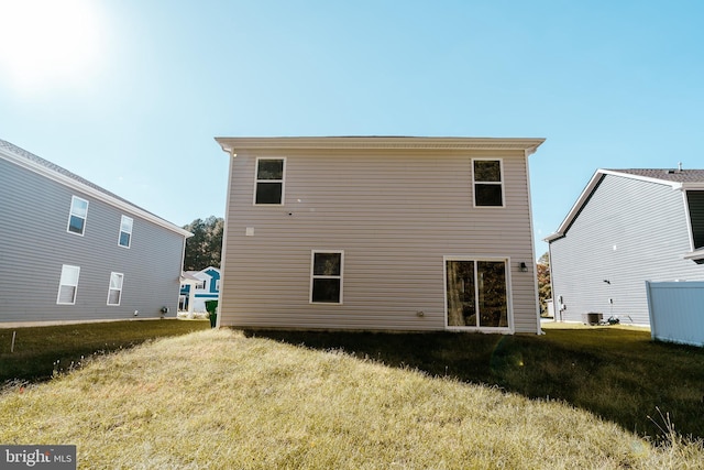 rear view of house featuring central air condition unit and a lawn