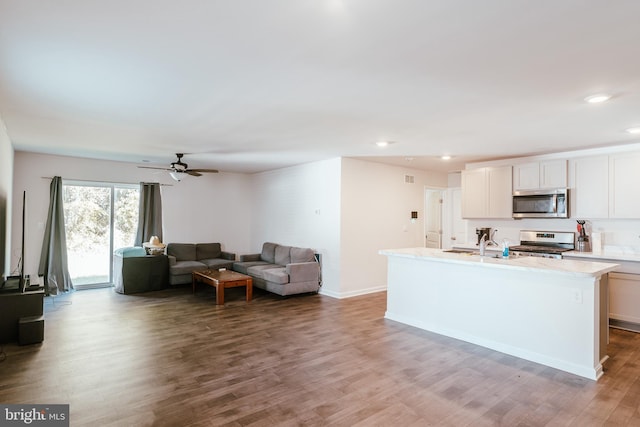 kitchen featuring appliances with stainless steel finishes, an island with sink, hardwood / wood-style floors, ceiling fan, and white cabinets