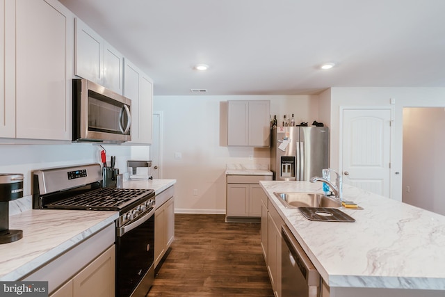 kitchen featuring appliances with stainless steel finishes, sink, white cabinets, dark hardwood / wood-style floors, and a kitchen island with sink