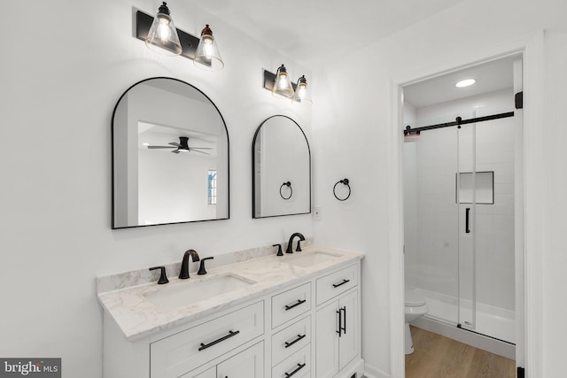 full bathroom featuring double vanity, a stall shower, a sink, and toilet