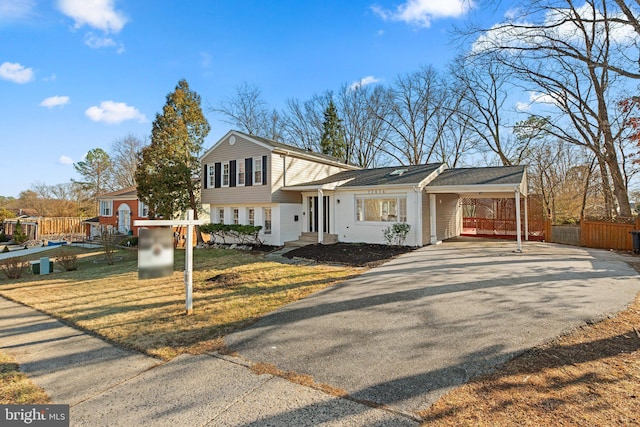 tri-level home with aphalt driveway, fence, and an attached carport