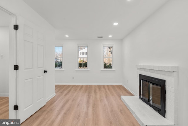 unfurnished living room with baseboards, visible vents, light wood-type flooring, a fireplace, and recessed lighting