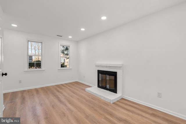 unfurnished living room featuring light wood-type flooring, a fireplace, baseboards, and recessed lighting