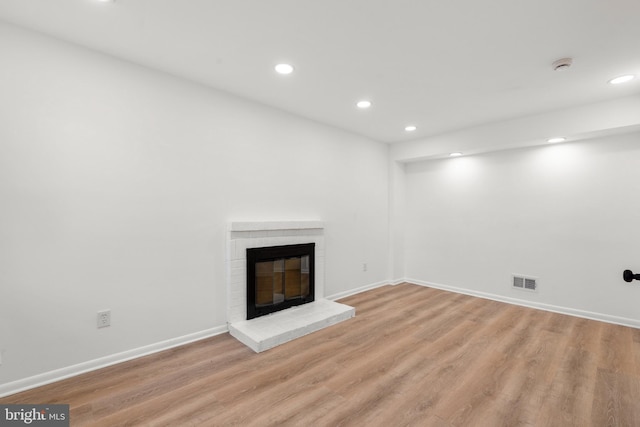 unfurnished living room featuring recessed lighting, visible vents, baseboards, light wood-style floors, and a brick fireplace