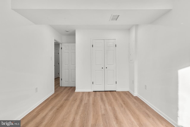 unfurnished bedroom with light wood-type flooring, visible vents, baseboards, and a closet