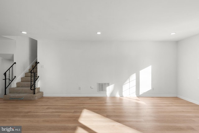 unfurnished living room featuring recessed lighting, wood finished floors, visible vents, and stairs