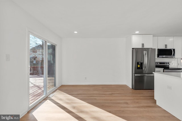 kitchen with light wood-style flooring, recessed lighting, white cabinetry, appliances with stainless steel finishes, and tasteful backsplash