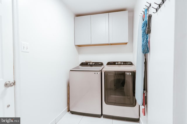 laundry area with washer and dryer, light tile patterned floors, and cabinets