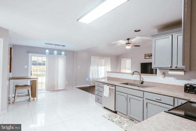 kitchen with gray cabinetry, sink, lofted ceiling, pendant lighting, and stainless steel dishwasher