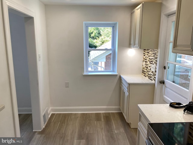 kitchen featuring cream cabinetry, decorative backsplash, light hardwood / wood-style flooring, and stove