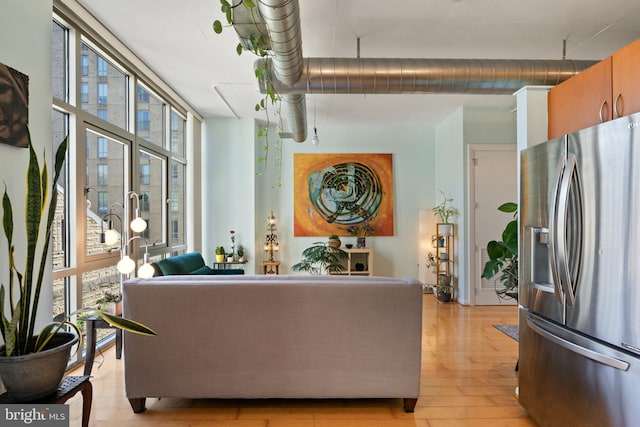 living room with a wealth of natural light, a wall of windows, and light hardwood / wood-style flooring