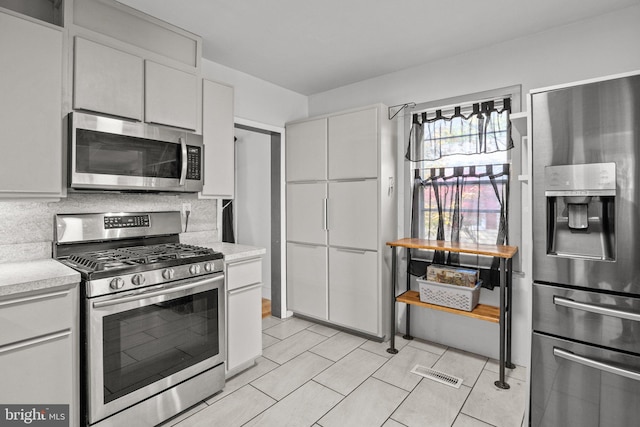 kitchen with decorative backsplash, white cabinetry, and stainless steel appliances