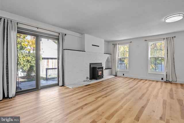 unfurnished living room featuring a wood stove and light wood-type flooring