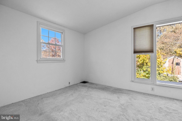 carpeted empty room with lofted ceiling