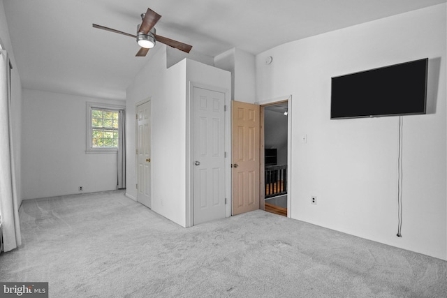 unfurnished bedroom featuring lofted ceiling, light colored carpet, and ceiling fan