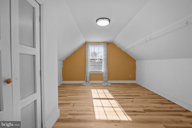 bonus room with vaulted ceiling and light wood-type flooring