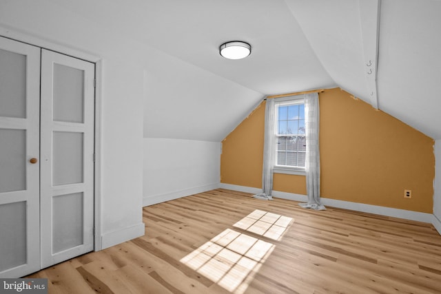 bonus room with light wood-type flooring and vaulted ceiling