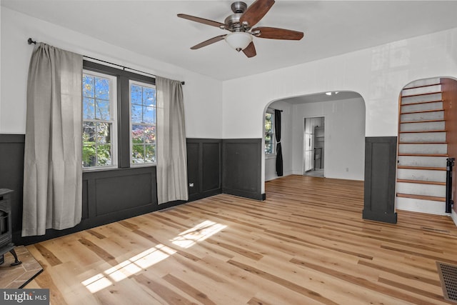 interior space featuring ceiling fan, a wood stove, and light hardwood / wood-style flooring