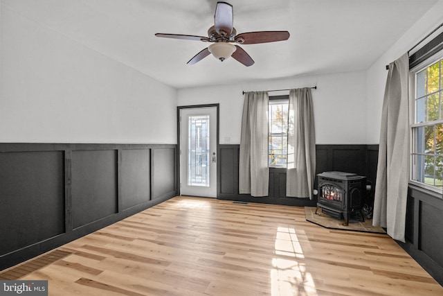 empty room featuring light hardwood / wood-style floors, a wood stove, and ceiling fan