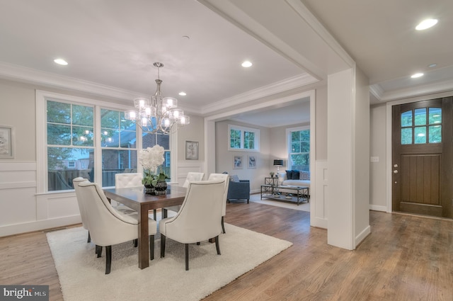 dining room featuring crown molding, light hardwood / wood-style flooring, and an inviting chandelier