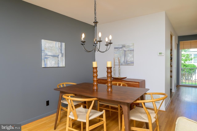 dining area with light hardwood / wood-style floors and an inviting chandelier