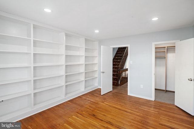 unfurnished bedroom featuring a walk in closet, a closet, and wood-type flooring