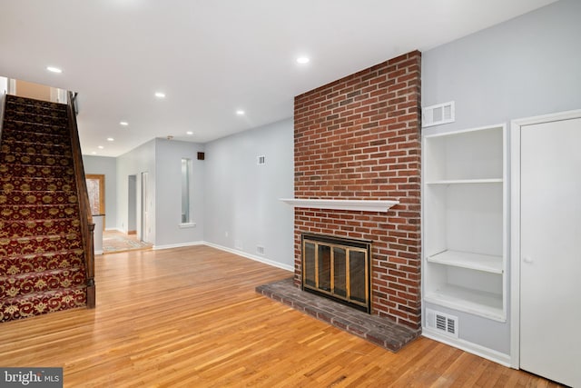 unfurnished living room featuring a brick fireplace and light wood-type flooring