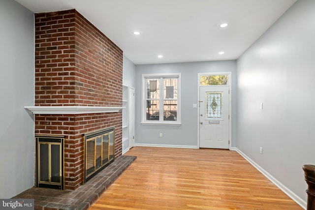 unfurnished living room with hardwood / wood-style floors and a brick fireplace