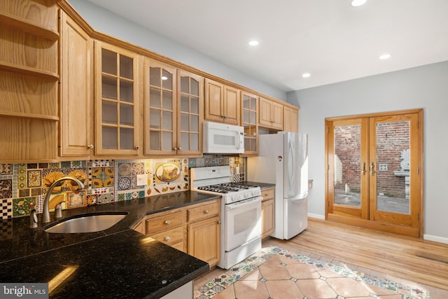 kitchen featuring tasteful backsplash, dark stone countertops, light hardwood / wood-style floors, sink, and white appliances