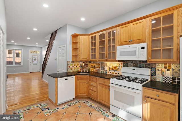 kitchen with white appliances, tasteful backsplash, sink, and dark stone countertops