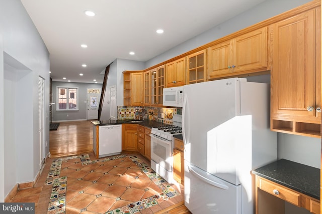 kitchen featuring backsplash, dark stone counters, light hardwood / wood-style flooring, sink, and white appliances