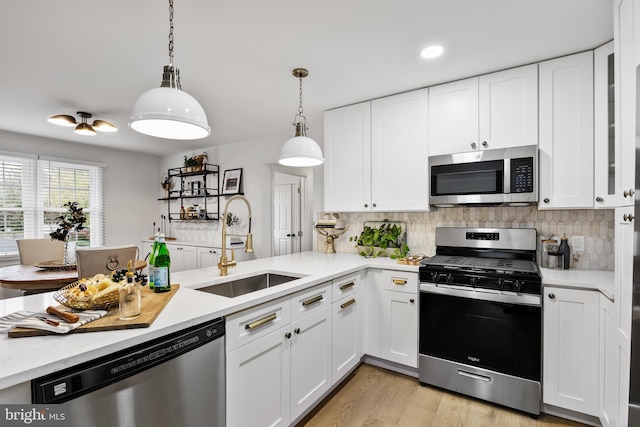 kitchen with white cabinets, pendant lighting, sink, and appliances with stainless steel finishes