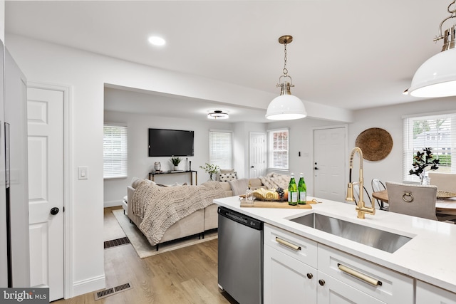 kitchen featuring pendant lighting, white cabinets, sink, light hardwood / wood-style flooring, and stainless steel dishwasher