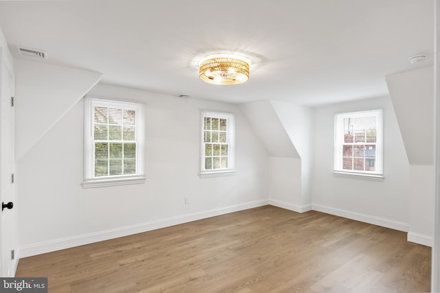 additional living space with light hardwood / wood-style floors and lofted ceiling